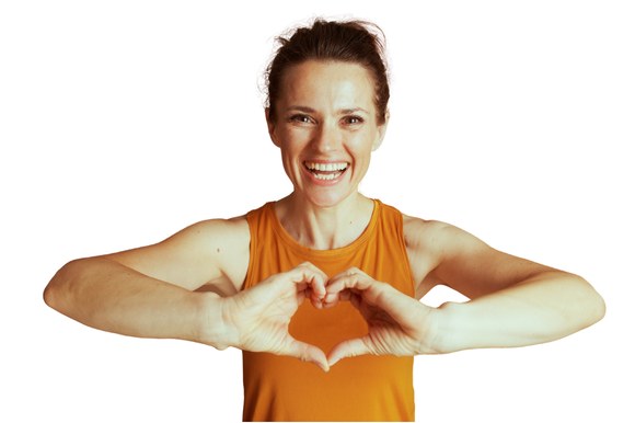 Smiling woman in an orange top making a heart shape with her hands